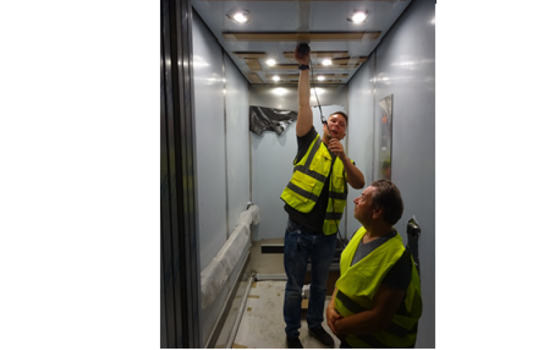 Zwei Männer in Schutzwesten bei Arbeiten in einem Aufzug