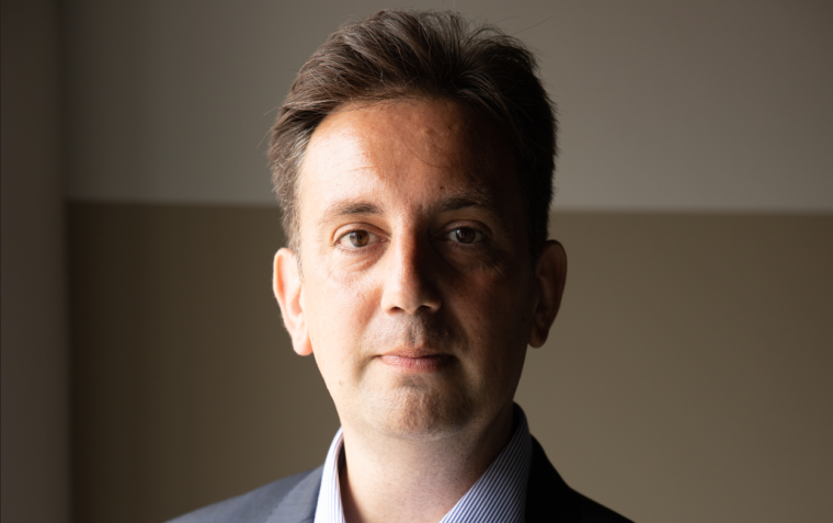 Ein Mann in dunkelblauem Anzug mit hellblau gestreiftem Hemd steht vor...