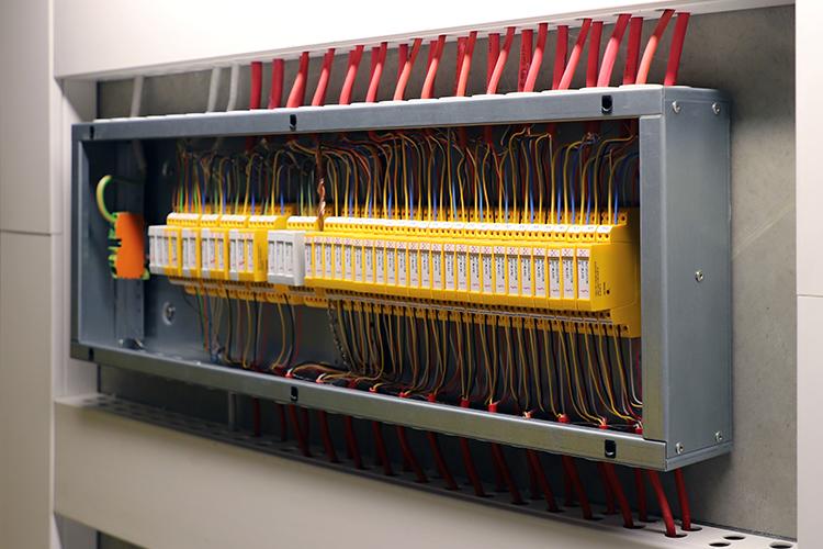 Offener Schaltschrank mit gelben Sicherheitsmodulen und zahlreichen farbigen...