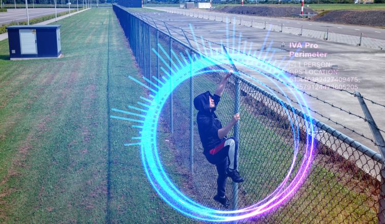 Luftaufnahme eines Geländes, auf dem eine Person einen hohen Zaun erklimmt,...