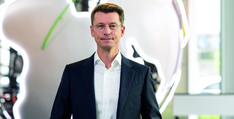 Person spricht in einem Seminarraum vor mehreren Teilnehmenden, neben einem...