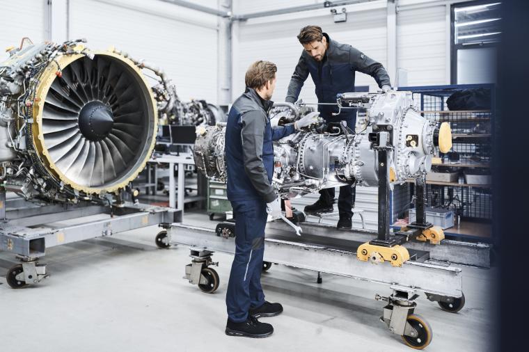 Zwei Personen arbeiten in einer Werkhalle an einem großen technischen...