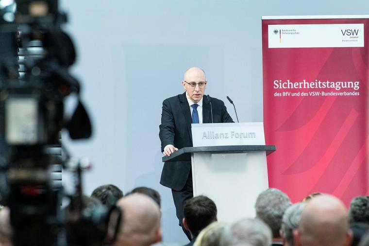 Mann mit Glatze und Brille spricht vor Publikum