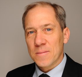 Person in schwarzem Anzug mit weißem Hemd und schwarzer Krawatte