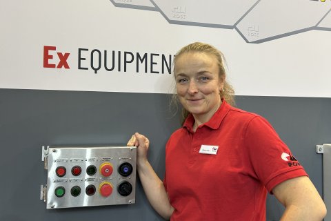 Blonde Frau vor Messewand