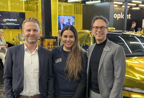 zwei Männer und eine Frau vor einem goldfarbenem Auto